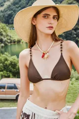 Collar de diseño artesanal con cordón grueso color crema, decorado con dijes metálicos dorados en forma de sol y un dije colgante en color rojo.