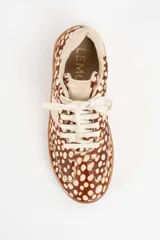 Zapatilla de cuero con textura de pelo y estampado animal print de puntos, con detalles en cuero liso color crema en los laterales y talón, y suela de goma color caramelo.