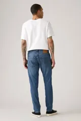 Pantalón de jean corte slim taper, con diseño de cinco bolsillos, cierre de cremallera y botón metálico, en tono azul medio con efecto lavado.