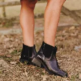 Bota corta tipo chelsea de cuero vacuno color negro, con puntera cuadrada, taco cuadrado de madera y detalle de textura grabada en el panel elástico lateral.