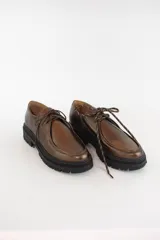 Zapatos tipo wallabee de cuero metalizado en tono peltre, con cordones negros y suela track de goma negra con plataforma.