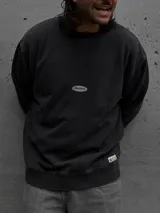 Buzo de algodón color negro, con cuello redondo, mangas largas y puños acanalados. Presenta un pequeño logo ovalado en el centro del pecho y una etiqueta pequeña en el ruedo.