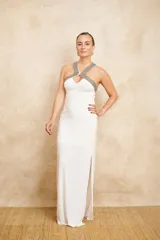 Vestido largo de jersey color blanco, con cuello halter bordado con mostacillas plateadas y tajo lateral en la falda.