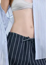 Pantalón de corte recto y tiro regular, confeccionado en algodón con diseño de rayas verticales. Presenta cintura elástica con cordón ajustable y bolsillos laterales.