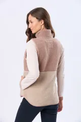 Chaleco de sherpa combinado en tonos beige, con cuello alto y cierre frontal. Presenta una textura suave y abrigada, ideal para capas adicionales.