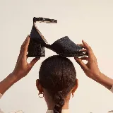 Sandalia de cuero negro con textura sutil, taco ancho y bajo, puntera abierta y tira ajustable en el tobillo.
