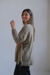 Sweater de punto con acabado brillante en tono verde oliva, de corte holgado y diseño con costuras verticales decorativas. Presenta cuello redondo y mangas largas con puños ajustados.