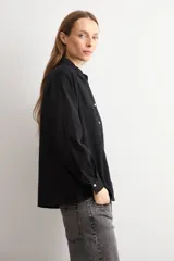 Camisa blanca de manga larga con frente de tela broderie con diseño de rombos calados y espalda lisa. Presenta cuello clásico y cierre frontal con botones.