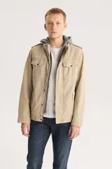 Campera color beige con capucha gris, cierre frontal con cremallera y botones a presión, cuatro bolsillos frontales con solapa y charreteras en los hombros.