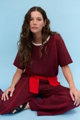 Blusa bordó de lino con mangas cortas, cuello redondo con ribete en contraste y costuras decorativas en zigzag de color rojo en el frente.