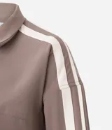Campera deportiva oversized de microfibra color marrón, con cuello alto, cierre frontal y bolsillos laterales. Presenta bandas laterales contrastantes en las mangas y cordón ajustable en el dobladillo.