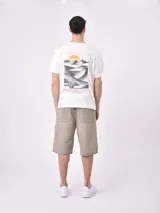 Remera de manga corta color beige claro, con cuello redondo y un pequeño estampado de un sol amarillo con texto en el pecho.