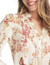Blusa de gasa con estampado floral y de mariposas, color beige. Presenta cuello a la base fruncido, escote en V con aplique de puntilla vertical en la parte delantera y cierre central con botones forrados. Posee mangas tres cuartos con puños abotonados.