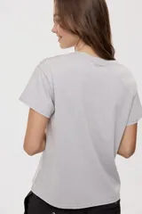 Remera de manga corta y cuello redondo color gris con efecto lavado, calce relajado y detalles de strass aplicados en la parte superior.
