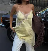 Vestido lencero corto color amarillo pastel, con tirantes finos y detalles de encaje blanco en el escote y el dobladillo.