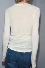 Camiseta blanca de manga larga, corte slim fit y escote pico pronunciado. Tejido ligero y ligeramente transparente con textura acanalada.