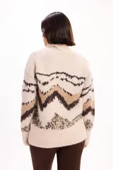 Buzo de tejido de punto con cuello alto, diseño de estampado geométrico en tonos beige, marrón y crema, de corte holgado y mangas largas.