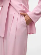 Pantalón sastrero wide leg rosado de tiro medio, con bolsillos delanteros, presillas para cinturón y raya marcada en las piernas.