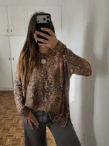 Sweater de punto con estampado de leopardo, cuello redondo y mangas largas, con diseño holgado y aberturas laterales en el bajo.
