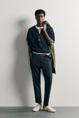 Pantalón chino negro slim fit de corte recto, con bolsillos frontales, trabillas para cinturón y cierre frontal con cremallera y botón.