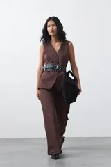 Chaleco sastrero de color marrón, con silueta recta, escote en V y cierre frontal con botones. Presenta una estructura definida y tejido con caída firme.