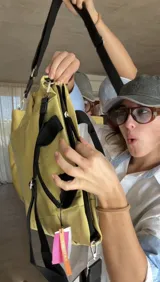 Cartera tipo tote de nylon color malva, con diseño capitoneado de líneas verticales en el frente y rombos en los laterales. Cuenta con doble asa de mano en color negro, bolsillos laterales y un parche decorativo con logo en la parte frontal.