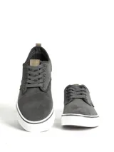 Zapatillas casuales de caña baja, color negro, con capellada de textil y suela de PVC blanca. Presentan cordones negros y detalles en cuero sintético marrón en la lengüeta.