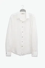 Camisa blanca de manga larga confeccionada en lino 100%, con calce recto y relajado. Presenta frente abotonado con botones de coco con logo y parche Polonio.