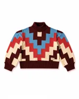 Sweater de cuello alto confeccionado en tejido de punto con diseño geométrico en bloques de colores bordó, rojo, celeste y beige. Presenta puños y ruedo acanalados y un pequeño parche decorativo en el frente.