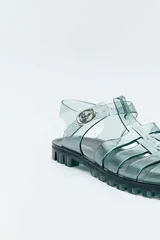 Sandalias estilo romano de PVC transparente en color verde, con suela track dentada y hebilla metálica lateral.