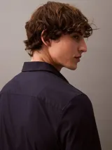 Camisa de manga larga Calvin Klein con corte slim, cuello clásico estructurado y cierre frontal con botones a tono. Presenta un diseño minimalista con monograma bordado en el pecho.