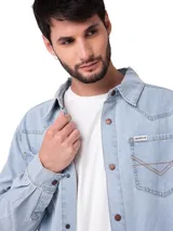 Camisa de denim celeste de manga larga, confeccionada en 100% algodón, con bolsillos frontales con solapa, canesú de estilo western y botones metálicos a presión.