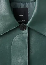 Chaqueta corta de efecto piel en color verde oscuro, con diseño recto, cuello camisero, manga larga y cierre frontal de botones ocultos. Presenta dos bolsillos de parche con solapa en la parte delantera y cuenta con forro interior.