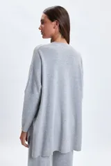 Buzo de punto oversize en color gris melange, con cuello redondo y mangas largas de corte caído.