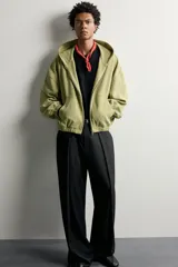 Cazadora relaxed fit de hombre, confeccionada en tejido estructurado tipo waffle con efecto lavado en color verde. Cuenta con cuello con capucha, cierre frontal con cremallera, bolsillos frontales tipo canguro y acabados elásticos en puños y bajo.