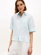 Camisa de manga corta Tommy Hilfiger de corte amplio y color celeste, confeccionada en puro lino. Presenta cuello inglés, bolsillo de parche en el pecho con logo bordado y hombros ligeramente caídos.