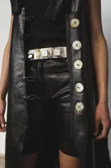 Bermuda de cuero color marrón oscuro con efecto desgastado, tiro medio, cierre frontal con botón y bolsillos.