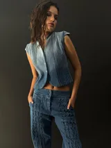 Chaleco de jean con cuello y pequeñas mangas, con alforzas texturizadas en los laterales.