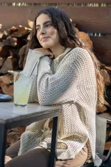 Camisa tejida en punto calado color marrón con hilo de algodón y lurex. Silueta oversize, mangas 3/4 ligeramente abullonadas, cuello camisero clásico y botonadura frontal con botones metálicos dorados.