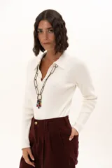 Sweater de tejido de punto fino color blanco, con cuello polo y escote en V, de manga larga y ajuste al cuerpo.