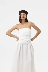 Vestido largo blanco con escote strapless y cuerpo fruncido. Posee falda amplia y fluida con bolsillos.