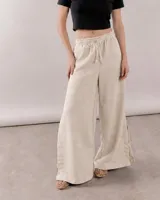 Pantalón de silueta amplia y calce relajado color beige, confeccionado en mezcla de lino y viscosa. Presenta cintura elastizada con lazo regulable y aberturas laterales en el bajo.