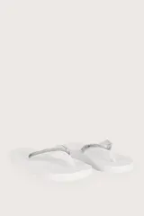 Sandalias bajas de dedo color blanco con tiras decoradas con pedrería plateada.