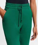 Pantalón de crepé rojo, modelo estilo pijama, de corte fluido, con cintura elástica y lazo de ajuste con terminales metálicas. Cuenta con bolsillos laterales y cierre frontal con cremallera y botón.