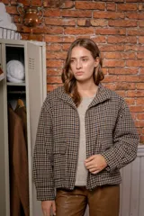 Campera de algodón con diseño de cuadros vichy en tonos beige y azul marino, corte recto, cuello alto y cierre frontal completo. Cuenta con bolsillos frontales con solapa y mangas largas.