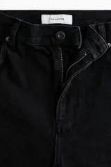 Jean negro de cinco bolsillos en denim de algodón rígido, con perneras amplias, tiro alto y detalles de crochet tono sobre tono en los laterales.