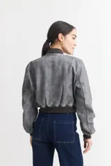 Campera bomber gris de cuero sintético con cuello, puños y ruedo acanalados.