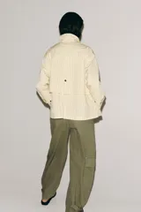 Chaqueta de corte recto confeccionada en algodón con estampado de cuadros. Presenta cuello solapa en color azul marino a contraste, cierre frontal con botones ocultos bajo solapa, bolsillos laterales y mangas largas con trabillas ajustables en los puños.
