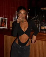 Body negro de manga larga con escote profundo y detalle de nudo en el centro, con aberturas laterales en la cintura.