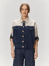 Chaqueta de lino de corte holgado en diseño color-block, combinando beige en la parte superior y azul marino en el cuerpo y mangas. Presenta cuello camisero, cierre frontal con botones de madera, bolsillos con solapa en el pecho y puños ajustables con presillas.